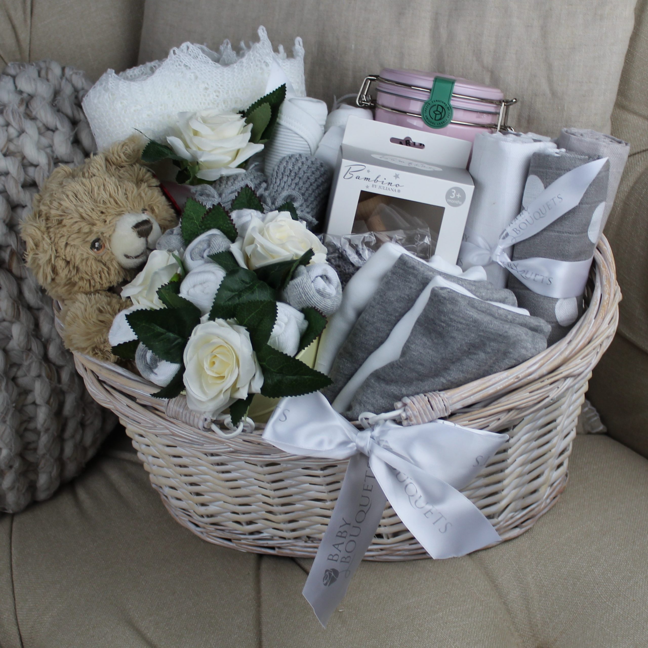 The Altura Hamper - Grey is a wicker basket packed fullof clothing and accessories for mother and baby