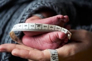 Close-up of the feet of a newborn baby on the palm of a mother.