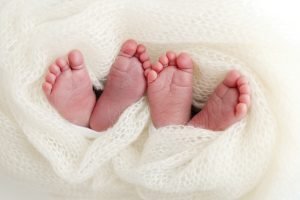 Photo of new born twins feet wrapped up in a shawl