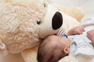Baby snuggled up with teddy bear